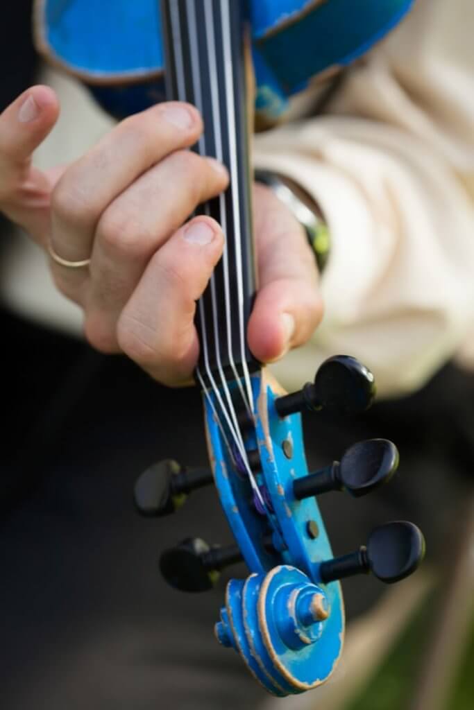 Man playing blue fiddle, pressing on strings.