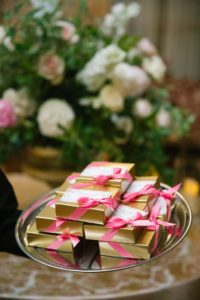 Wedding Favors: gold foil chocolate boxes tied with a pink ribbon, adorned with a handpainted favor tag.