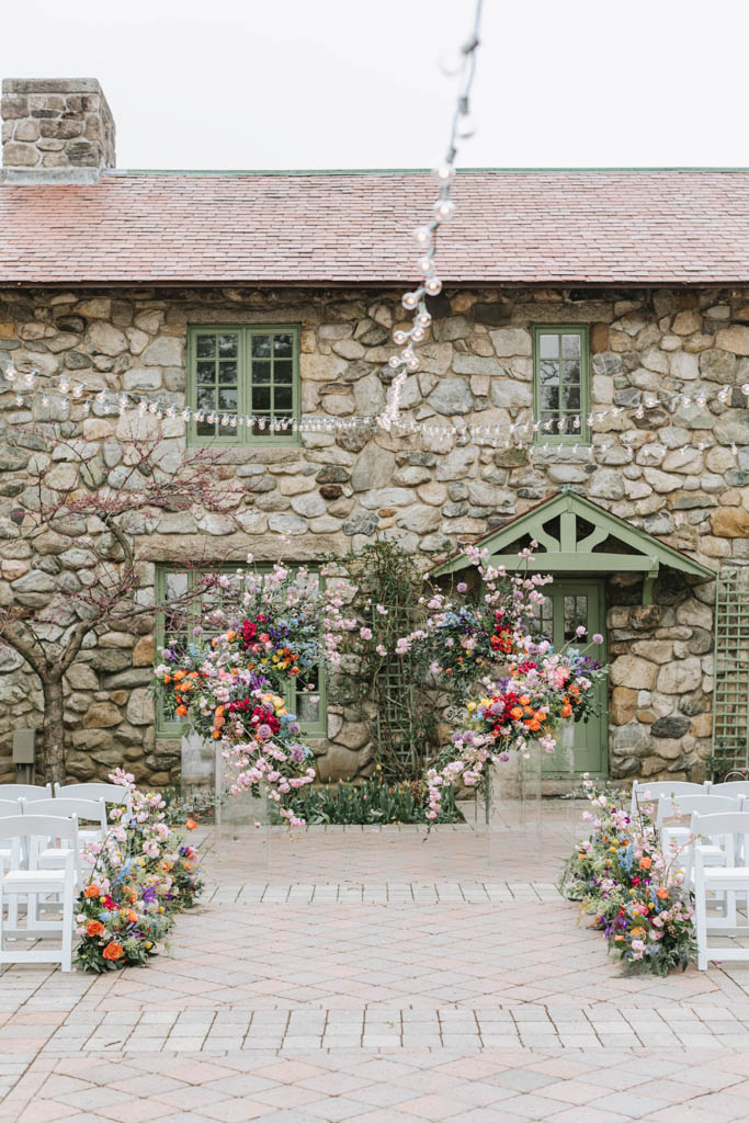 Colorful floral arch and aisle markers at outdoor ceremony at Willowdale Estate venue in Massachusetts 