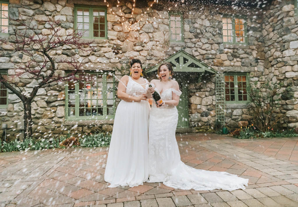 Brides popping champagne at Willowdale Estate Massachusetts wedding 