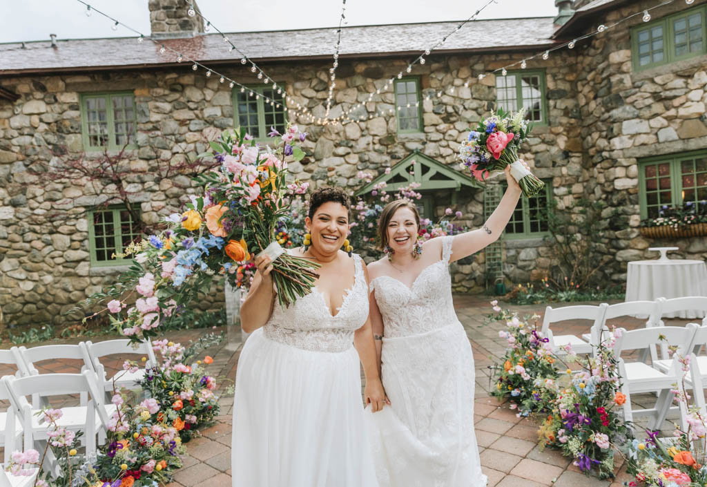 Brides smiling with bouquets at outdoor ceremony at Willowdale Estate venue in Massachusetts 